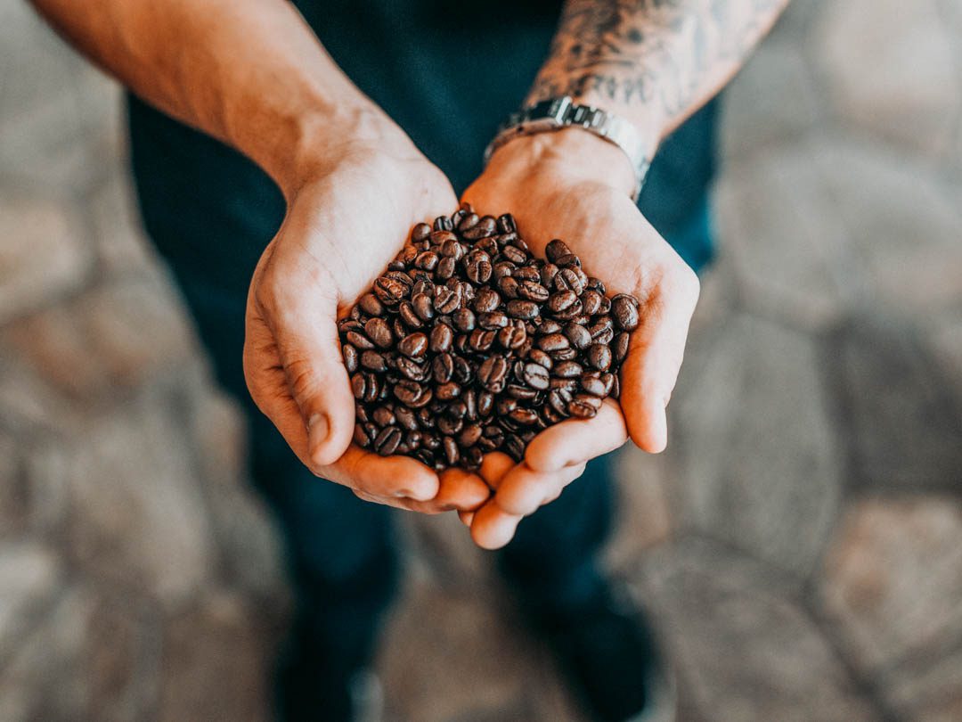 Handful of coffee beans awaiting one of the best manual coffee grinders to get the best results