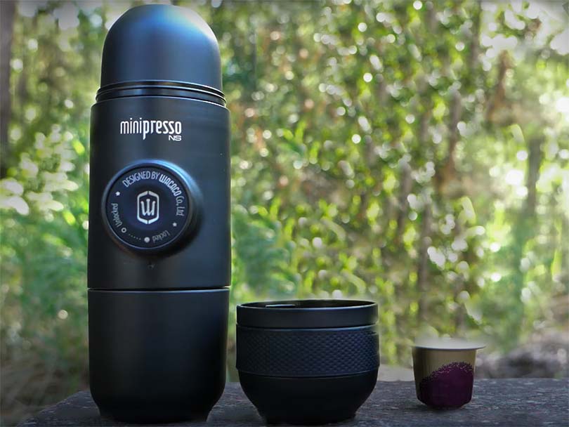 Wacaco Minipresso on outdoor table beside cup and Nespresso pod