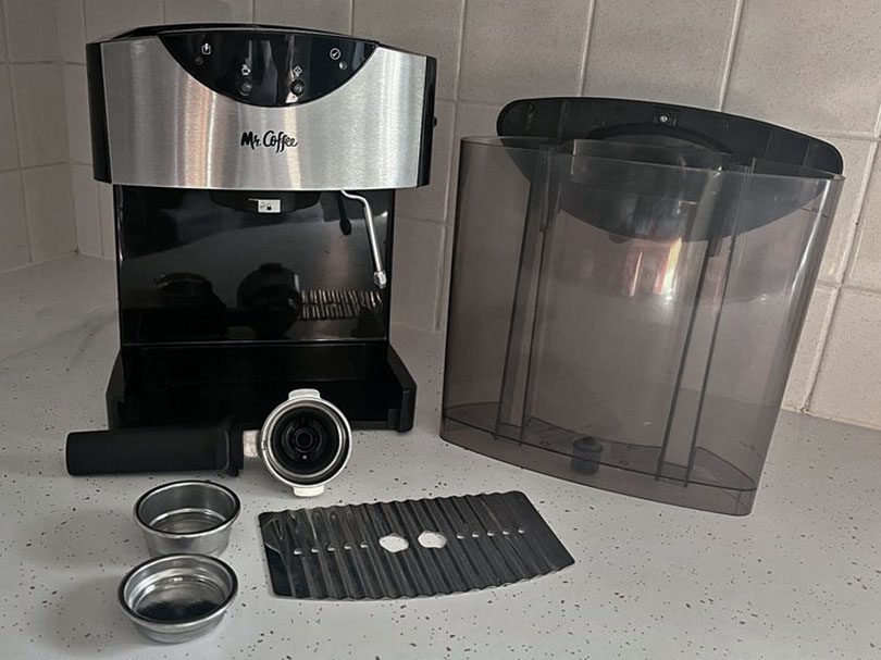 Mr Coffee ECMP50 with the portafilter, filter baskets, drip tray, and water tank lying separately on kitchen counter