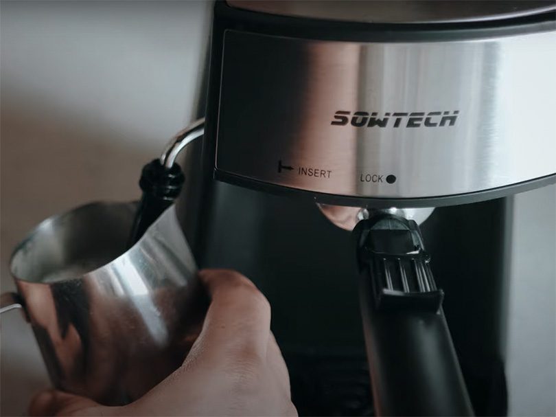 The Sowtech espresso machine frothing milk in metal milk pitcher
