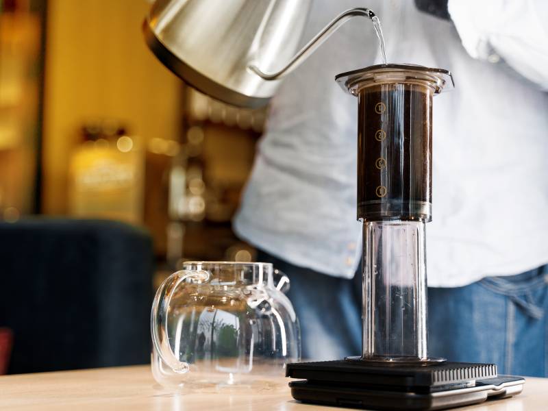 AeroPress coffee maker on scale, water being poured into it