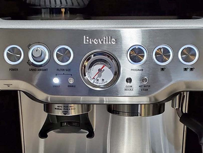 Close-up of the buttons, dial, and pressure gauge on the Breville Barista Express