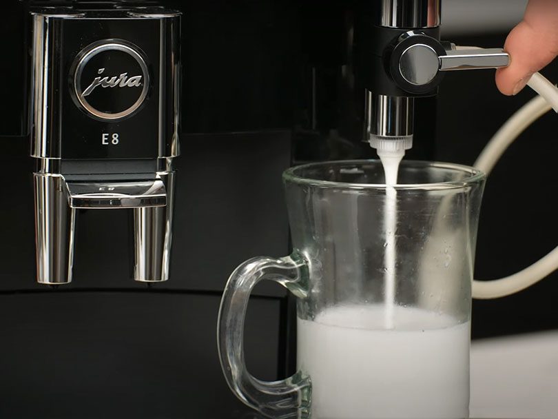 Finger moving the milk adjustment dial on the Jura E8