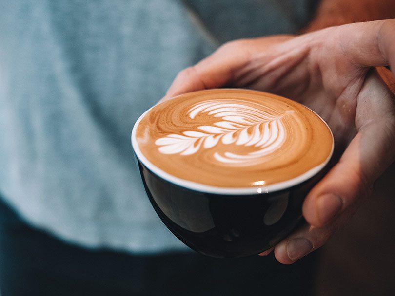 Man's hand holding a flat white