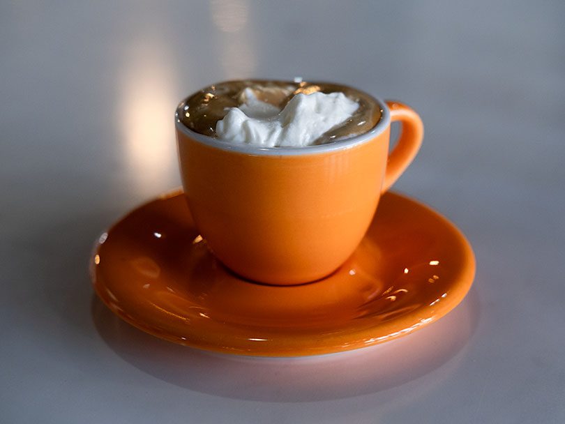 Espresso con panna in an orange cup - lots of whipped cream on an espresso shot