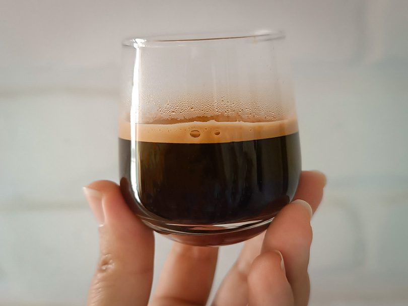 Holding a shot of espresso up to the camera