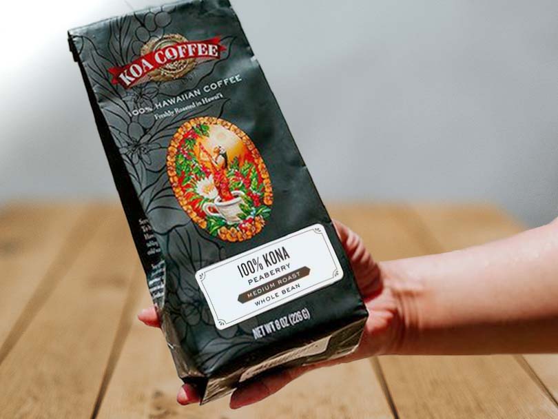 Hand holding a bag of Koa Coffee 100% Kona Peaberry (Medium Roast)