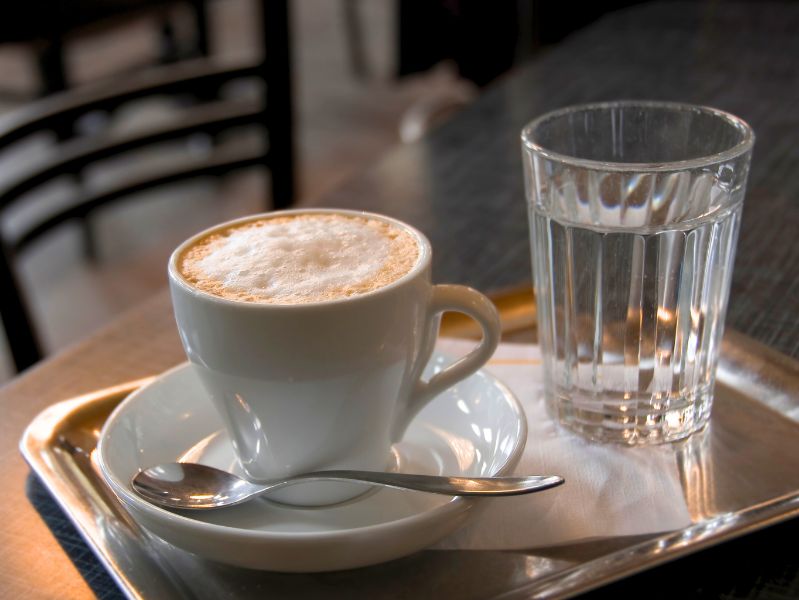 A mug of Melange - traditional Viennese coffee with milk and sugar, served with a glass of water