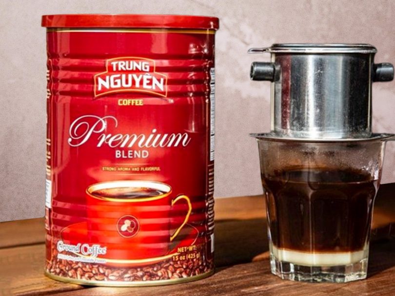 Can of Trung Nguyen Coffee (Premium Blend) beside a phin of cà phê sữa (Vietnamese coffee with condensed milk)