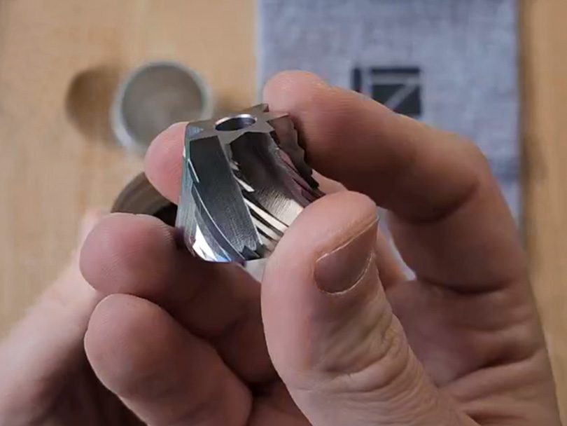 Holding the 1Zpresso Q2's heptagonal burrs up to the camera