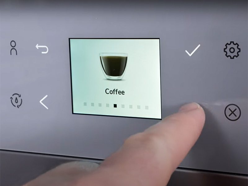 Finger pressing button on KitchenAid KF6 to scroll through drinks selection, Coffee is displayed on screen
