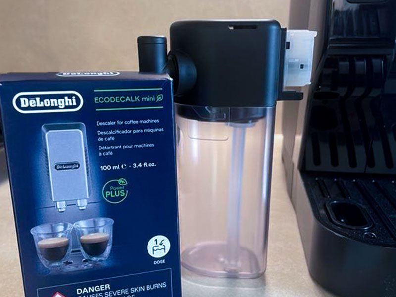 A box of DeLonghi EcoDecalk and LatteCrema milk container sitting beside espresso machine