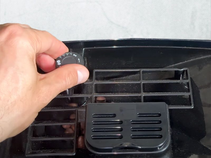 Close up of the built-in grinder and adjustment dial on the DeLonghi Magnifica Start