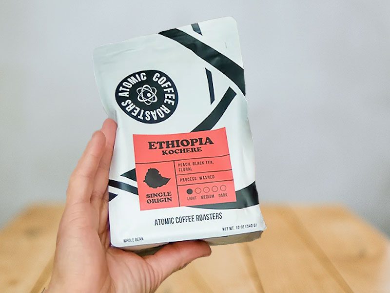 Hand holding up a bag of Atomic Coffee Roasters Ethiopia Kochere coffee beans