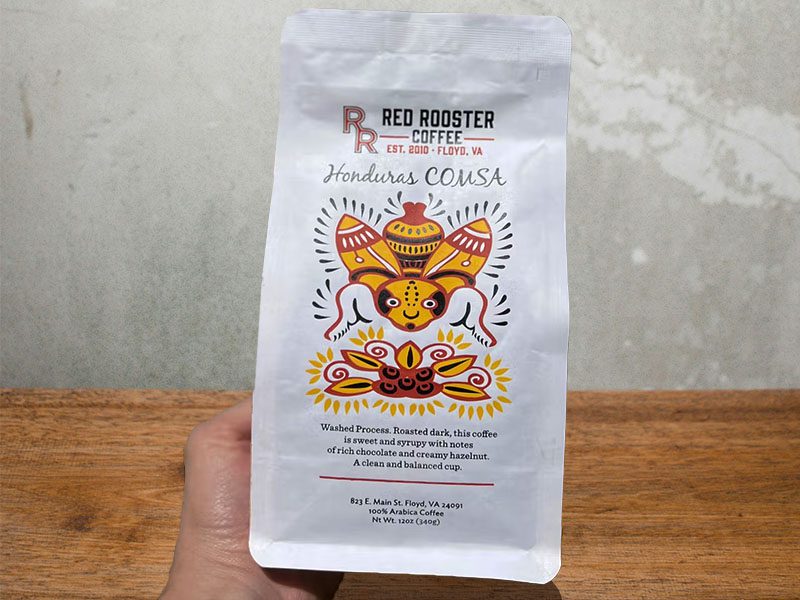 Holding a bag of Red Rooster Coffee - Honduras Comsa